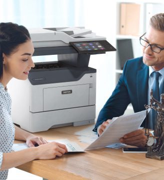 Un uomo e una donna seduti a un tavolo, impegnati in una conversazione mentre una stampante Xerox® è posizionata nelle vicinanze. Un uomo e una donna seduti a un tavolo, impegnati in una conversazione mentre una stampante Xerox® è posizionata nelle vicinanze.
